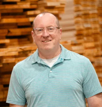 Portrait of Jeff Walters from Big Sky Doors, standing in front of stacked wood panels in the Montana production facility.